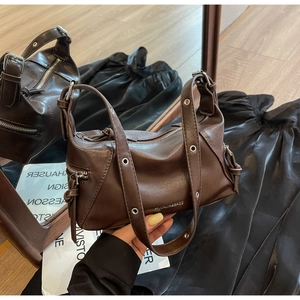 Close-up of dark brown leather tote bag with silver eyelet strap and metallic brand logo