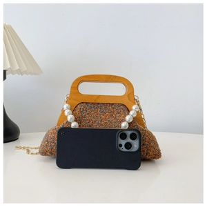 Detail of tweed evening bag with wooden handle and pearls next to a phone for scale