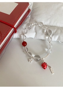 Close-up of glass beaded strawberry bracelet with silver flower charms and heart tag