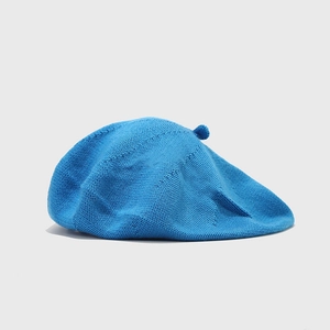 Close-up of bright blue knitted cotton beret with top pompom showing fine texture