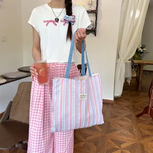 Dettaglio della borsa tote a righe con etichetta zakka beauté e design casual pastello