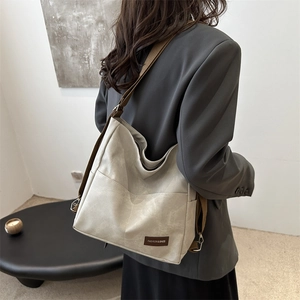 Grey-white large hobo tote bag with brown straps shown on shoulder in office setting