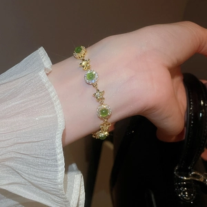 Detailed macro of vintage gold star bracelet with green stones and pearl accents