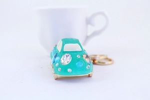 Close-up of cyan rhinestone car keychain with gold metal ring on white background