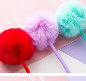 Close-up of cute fluffy pom-pom pens in red, purple, and mint green colors