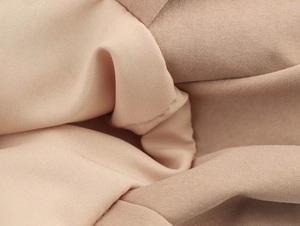 Macro della trama del tessuto twill beige e cuciture sui pantaloncini a palloncino