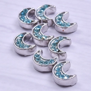 Macro shot of silver moon charms with light blue rhinestones for DIY jewelry