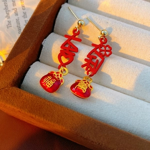Detail of red enamel lucky bag earrings with golden Chinese characters and hollow patterns