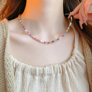 Close-up of colorful beads, small pearls, and gold spacers necklace on a model's collarbone