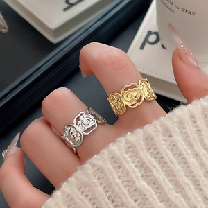 Detail von gold- und silberfarbenen Ringen mit strukturierter Blumenform an der Hand