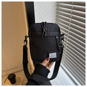 Detail of a black nylon crossbody bag featuring the Hello Weekend text label and zipper