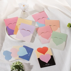 Colorful heart-shaped paper greeting cards with Best Wishes text on white fabric