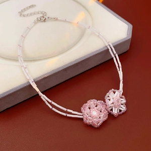 Detail of double-layer beaded necklace with pink and white flowers on jewelry box