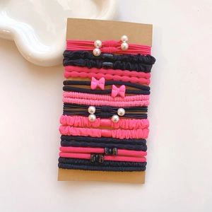 Pink and black elastic hair ties set with pearls and bows on a brown card display