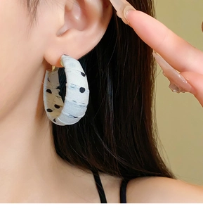 Detailed view of polka dot fabric hoop earrings on model with retro French style finish