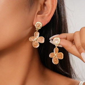Elegant gold flower earrings with brown enamel texture on a model's ear, vintage style