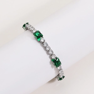 Close-up of silver tennis bracelet with emerald green squares and round cubic zirconia
