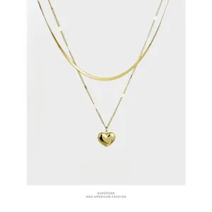 Macro view of double-layer gold snake chain featuring a solid heart pendant necklace