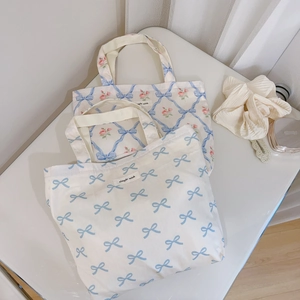Detailed close-up of floral canvas tote bags with blue bows and rose patterns