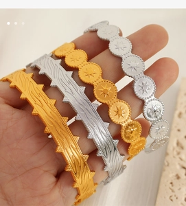 Close-up of gold and silver open bangles with star relief and thorn texture detail