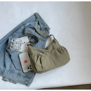 Olive green crescent shoulder bag with drawstring pockets on denim jacket