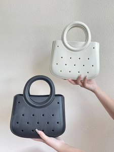 Détail de mini sacs de plage en EVA au design ajouré en coloris noir et blanc crème