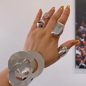 Detail of model wearing a stacked silver stainless steel bangle and unique geometric rings