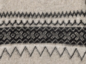 Detailed close-up of geometric Fair Isle knit texture in beige and dark grey wool