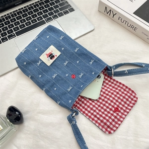 Detail van denim telefoontasje met kattenpatch, sterborduurwerk en ruitjesvoering