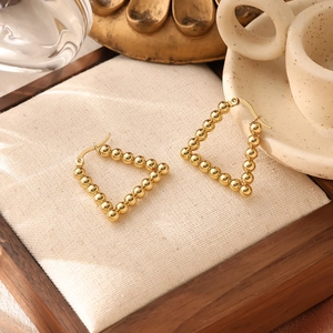 Detail of 18K gold plated triangular beaded hoop earrings on a wooden display tray