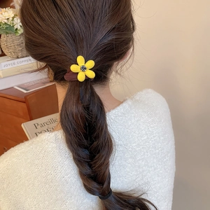 Détail d'un chouchou fleur jaune floqué avec strass coiffé dans une tresse en épi