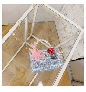 Detail of tweed crossbody bag with gold chain, pearl handle and pink bunny mascot