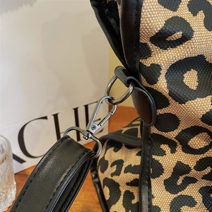 Close-up of gunmetal hardware buckle and black leather strap on leopard print bag