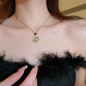 Detailed view of a gold coin pendant featuring a blue gemstone and vintage portrait relief