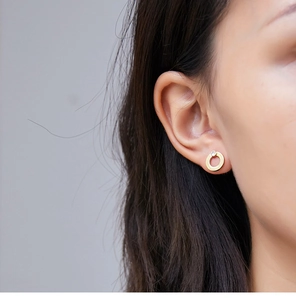 Close-up of minimalist geometric gold hoop earrings with sparkling diamond studs