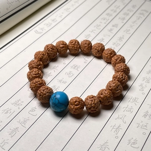 Close-up of Rudraksha seed bracelet with natural texture and a single blue turquoise bead