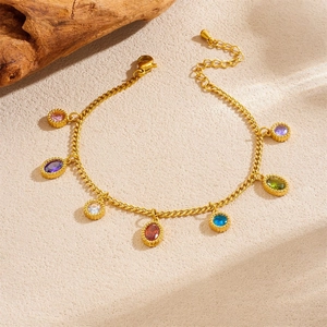 Elegant gold chain bracelet featuring colorful gemstone charms on a beige textured surface