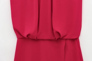 Detail view of deep red sleeveless romper showing elegant waist pleats and soft draped fabric
