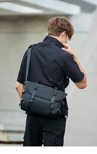 Detailed back view of a black tactical messenger bag worn by a model in modern urban setting