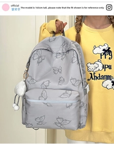 Detail view of grey butterfly print backpack with fluffy cloud charm on model