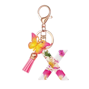 Macro view of resin letter X keychain with pink floral filling and a silk tassel