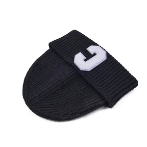 Close-up of black ribbed knit beanie featuring a white letter C embroidered patch