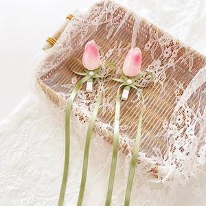 Elegant pink tulip hair clips with ribbons and pearl accents on white lace background
