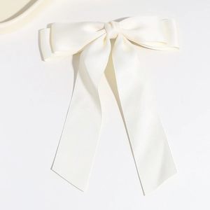 Close-up of elegant cream white satin bow hair clip with long flowing ribbons