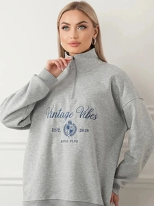 Detailaufnahme des grauen Sweatshirts mit halbem Reißverschluss und Vintage-Aufdruck