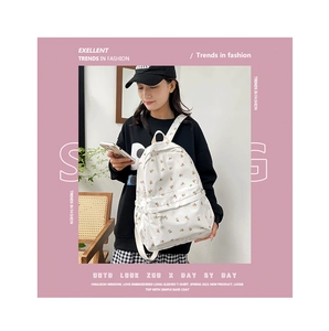 Close-up of a white canvas floral backpack featuring pink flower patterns on the fabric