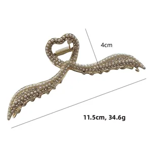 Dettaglio elegante molletta per capelli dorata con perle, strass e manico a cuore