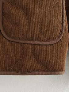 Detail van bruin corduroy jack met gewatteerde textuur en verstevigde naden van de zak