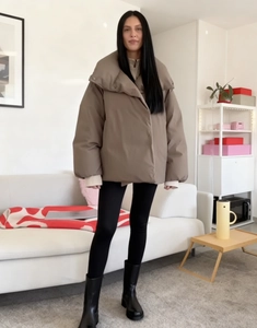 Close-up of a brown puffer jacket with stand collar and quilted texture in a living room