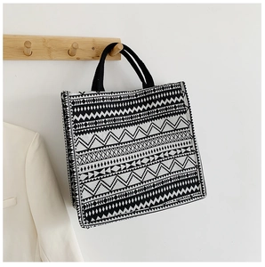 Detail view of woven tote bag with black and white tribal patterns on a wooden hanger